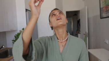 Genç bir kadın zarif bir şekilde tütsü çubuğuyla bağlanır ve parlak mutfağında huzurlu bir atmosfer yaratır.