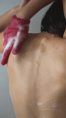 Bir insan deri sağlığını ve güzelliğini geliştirmek için fırçalama eldiveni kullanarak sırtında deri dökülmesini gösterir.