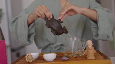 Huzurlu bir çay hazırlama sahnesinde büyüleyici küçük heykelcikler eşliğinde eşsiz bir çaydanlık sergileniyor.