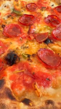 Yakından bakınca, ağız sulandıran biberli pizzayı eritilmiş peynir ve çıtır çıtır bir kabukla gösteriyor.