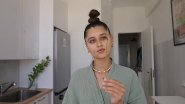 Genç bir kadın, modern mutfak düzeniyle çevrili iken yaratıcı bir şekilde sopayla kendini gösteriyor.