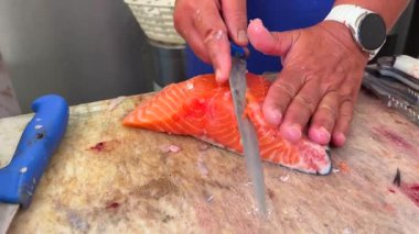 Yetenekli ellere dikkat et, fileto fileto taze somon, gerçek aşçılık hassasiyetini ve sanatsal beceriyi gösteriyor.