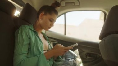 Genç bir kadın tesadüfen arabanın arkasında oturur, akıllı telefonuyla meşgul olur ve gününün tadını çıkarır.