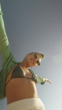 Canlı ve hayat dolu bir birey dışarıda sahildeki parlak güneşin tadını çıkarırken mutluluğu ifade ediyor.