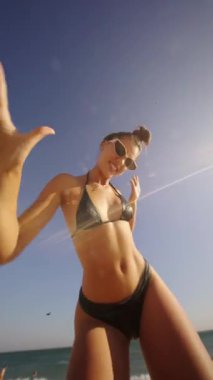 Canlı bir plaj sahnesi, genç bir kadını okyanus dalgaları tarafından yazın heyecanla kucaklanan zevklerini yakalar.