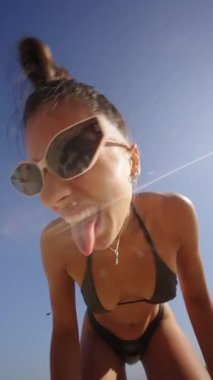 Güzel, güneşli bir plaj gününün tadını çıkarıyorum. Neşeli pozlar, şık güneş gözlükleri, parlak yaz enerjisi.