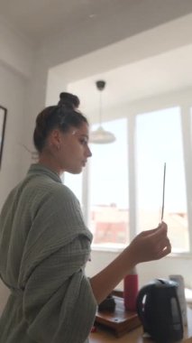 Bir kadın, güneşli bir mutfakta huzur verici ve sakinleştirici bir ayin yapar. Huzur hissi yayar.