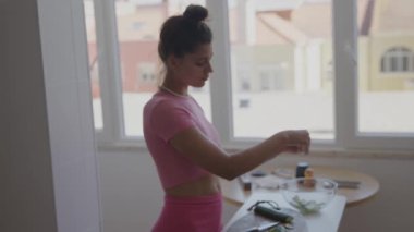 Pembe elbiseli genç bir kadın güzel bir mutfakta taze sebzeleri ustalıkla doğruyor.