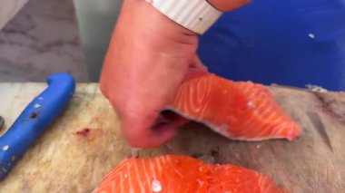 Bu yüksek kaliteli görüntülerde yetenekli eller çeşitli mutfak uygulamaları için taze somonları ustalıkla fileto ediyor.