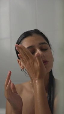 Bir insan dinçleştirici bir cilt bakım rutinine tutkulu bir şekilde bağlanır ve rahatlatıcı duşun tadını çıkarır.