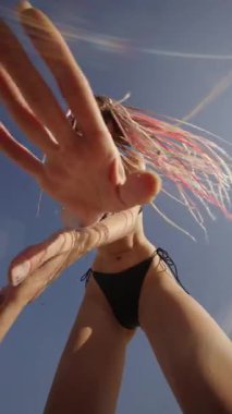 Sahilde canlı ve dinamik bir sahne. Parlak ve güneşli bir gökyüzüne karşı neşeli dans hareketleri sergiliyor.