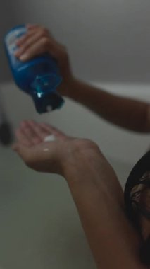 Saç bakım rutininin detaylı bir yakın çekimi banyoda dinlenirken şampuanın uygulanmasını vurguluyor.