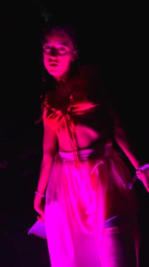 Büyüleyici bir dansçı, canlı neon ışıkların arasında sanatsal bir performans sergiliyor.