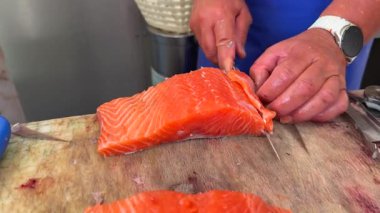 Uzman eller taze somonu ustalıkla fileto yaparak etkileyici yemek yapma becerilerini sergiliyor.