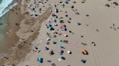 Renkli şemsiyeler ve neşe dolu kumsallarla dolu güzel bir kumsalın canlı hava manzarasının tadını çıkarın.