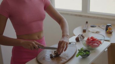 Bir kadın, sağlıklı yemek pişirmek için modern bir mutfak alanında özenle taze ve renkli malzemeler hazırlıyor.