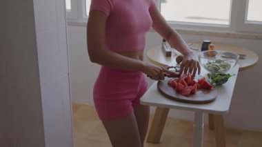 Parlak, neşeli bir mutfakta besleyici bir yemek hazırlamak için taze, renkli sebzeler dilimleyen bir insan.