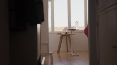 Pembe elbiseli genç bir kadın, sağlıklı bir yaşam tarzının göstergesi olarak güneşli bir mutfak ortamında yemek hazırlıyor..