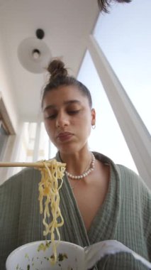 Bir kadın bu öğlen, öğle yemeği çubuklarıyla lezzetli eriştelerin tadını çıkarıyor.