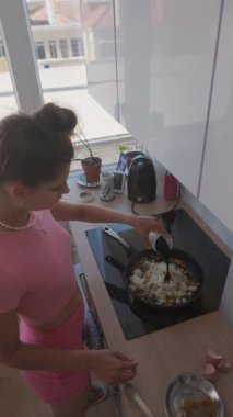 Bir kadın, güneş ışığıyla dolu parlak ve modern bir mutfakta ustalıkla lezzetli ve sağlıklı bir yemek hazırlar.