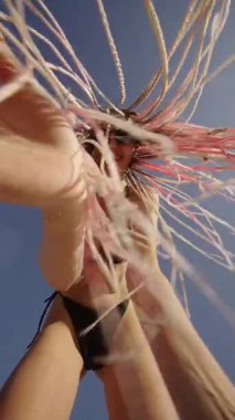 Genç bir kadın neşeli bir şekilde kumsalda güneşli bir günün tadını çıkarıyor. Canlı enerjisini ve eşsiz tarzını sergiliyor.