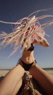 Sahilde göz kamaştırıcı ve enerjik bir görüntü. Canlı saçlar ve renkli bikiniler giymiş neşeli pozlar.