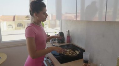 Genç bir kadın, aydınlık ve havadar bir mutfak ortamında özenle lezzetli bir yemek hazırlıyor.