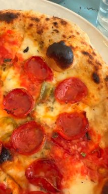 Bu, eritilmiş peynirini ve canlı malzemelerini sergileyen lezzetli bir biberli pizzanın yakın plan fotoğrafı.