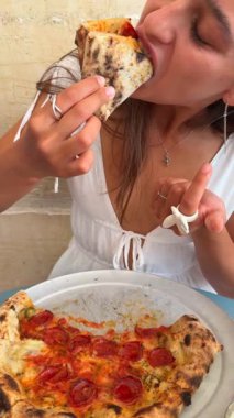 Genç bir insan sıcak ve sıcak bir yemek atmosferinde lezzetli bir pizza diliminin tadını çıkarmaktan mutlu olur.