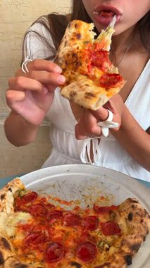 Bir insan bir dilim biberli pizzadan zevk alır, neşe veren yiyeceklerin sergilenmesi büyüleyici bir atmosfer sağlar.