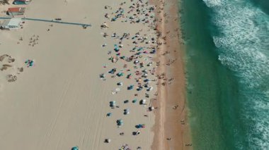 Güneş banyosu ve renkli şemsiyelerle dolu canlı bir plaj sahnesi keşfedin.