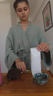 Genç bir insan sakin ve dingin bir çay hazırlama sürecine girer. Bu da farkındalığı ve rahatlamayı yansıtır.