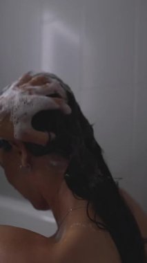 Sıcak bir duşta şampuan kullanan, özen ve refahı ön plana çıkaran huzurlu bir banyo sahnesi.