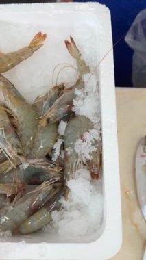 Yakından bakıldığında taze karideslerin buzda sergilendiği ve deniz ürünleri pazarında satışa sunulduğu bir manzara.