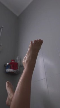 Duşun altındaki bacakları tasvir eden sakin bir an. Rahatlamanın ve genel olarak sağlığın önemini vurgulayan.