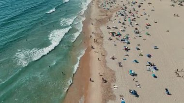 Sahilde neşeli güneşlenenlerle, renkli şemsiyelerle ve nazik okyanus dalgalarıyla dolu fantastik bir günün tadını çıkar.
