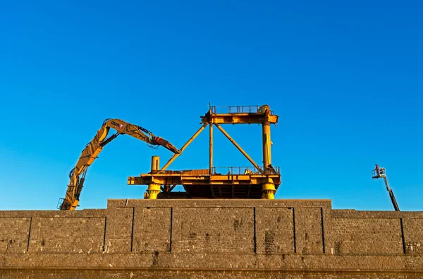 The late afternoon sun shines on workers demolishing art installation See Monster in Weston-super-Mare, UK on 16 January 2023