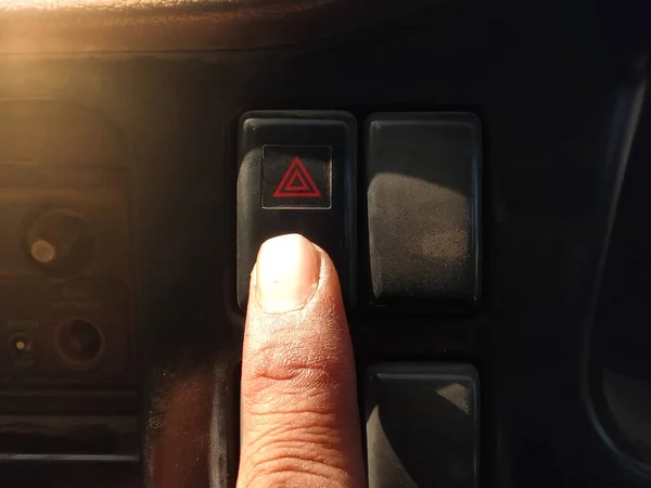 Finger press the emergency light button with the red triangle symbol.