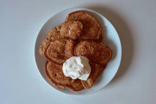 Keto badem unlu krep beyaz bir tabakta ve üzerinde Yunan yoğurdu var. Sağlıklı düşük karbonhidratlı kahvaltı seçeneği, temiz yemek ve ketojenik diyetler için mükemmel..