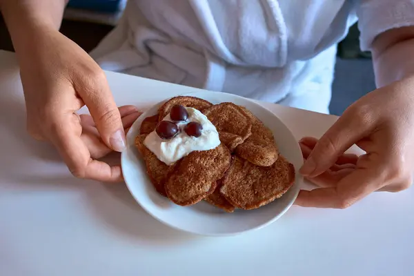 Beyaz bir tabakta yoğurt ve üzümle kaplı ev yapımı keto krepleri. Elle servis edilen düşük karbonhidratlı bir kahvaltı. Besleyici bir başlangıç için mükemmel..