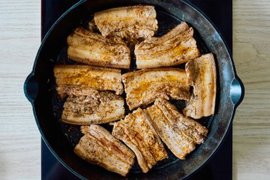 Baharatlı domuz eti dilimli kızarmış domuz eti, dökme demir tavada pişirilmiş, kahverengiye boyanmış ve servise hazır. Geleneksel et yemeği hazırlıklarına yakın çekim.