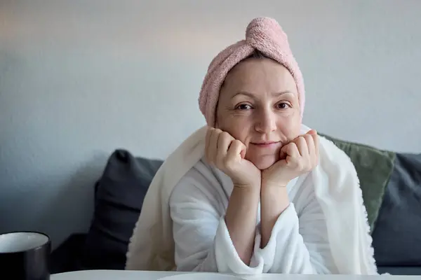 Kafasında havluyla rahat bir kadın. Sabahın tadını çıkarıyor, kanepede kahve içiyor..                          