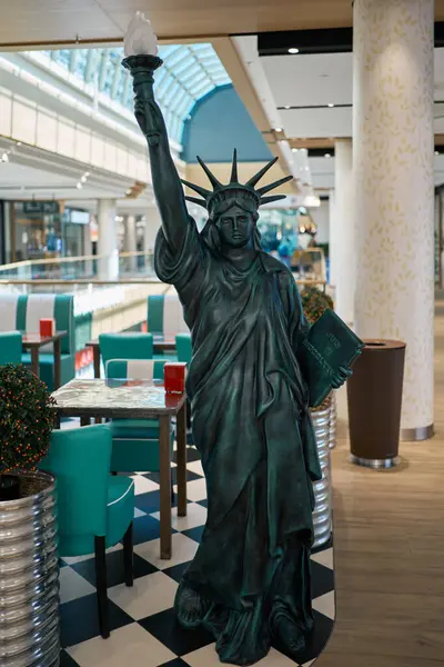 Fuerth, Almanya, Bavyera 15 Mayıs 2025: Özgürlük Anıtı 'nın bir kopyası, deniz mavisi sandalyeler, kareli döşemeler ve çağdaş dekor içeren modern bir alışveriş merkezinde duruyor..