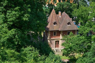 Dikenli kiremit çatılı pitoresk bir tuğla ve taş ev yemyeşil ağaçlarla çevrilidir. Tuhaf mimari stil ve huzurlu ortam huzurlu bir geri çekilme için mükemmel bir peri masalı ortamı yaratıyor..