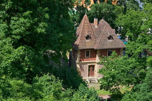 Dikenli kiremit çatılı pitoresk bir tuğla ve taş ev yemyeşil ağaçlarla çevrilidir. Tuhaf mimari stil ve huzurlu ortam huzurlu bir geri çekilme için mükemmel bir peri masalı ortamı yaratıyor..