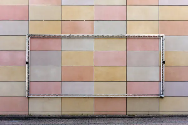 Geometrik duvar, Pastel paneller ve reklam için boş metal çerçeve yapısı. Simetri ve sessiz renklere sahip kentsel cephe tasarımı, arkaplan veya mimari kavram için ideal.