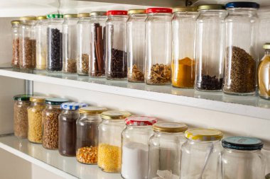 Duvar rafında toplu yiyecekler olan cam konteynırların yan görüntüsü. Sanayileşmiş ürünler için cam ambalajının yeniden kullanımı.