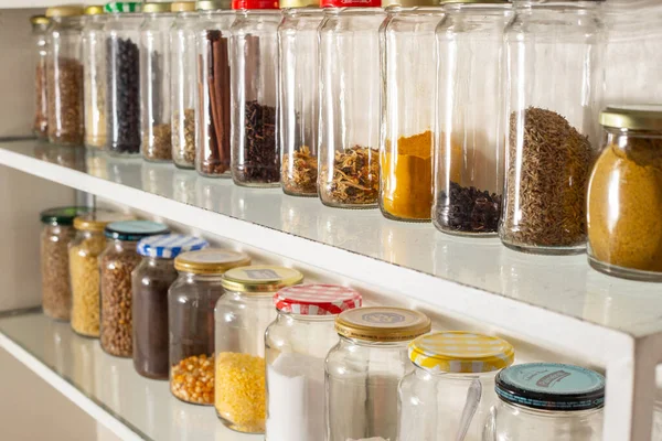 Side view of some glass containers with bulk food on a wall shelf. Reuse of glass packaging for industrialized products.