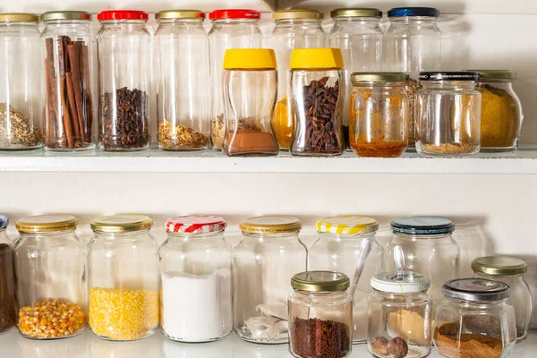 Front view of some glass containers with bulk food on a wall shelf. Reuse of glass packaging for industrialized products.