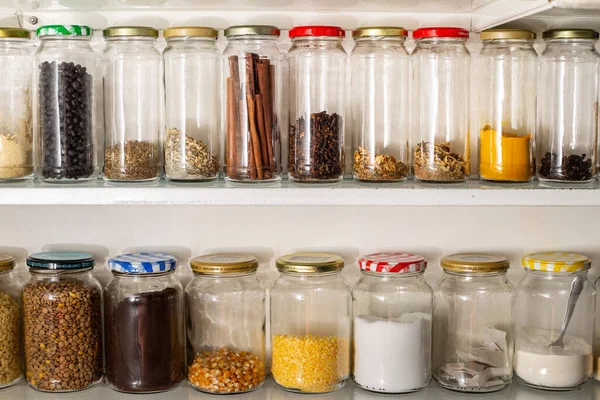 Front view of some glass containers with bulk food on a wall shelf. Reuse of glass packaging for industrialized products.